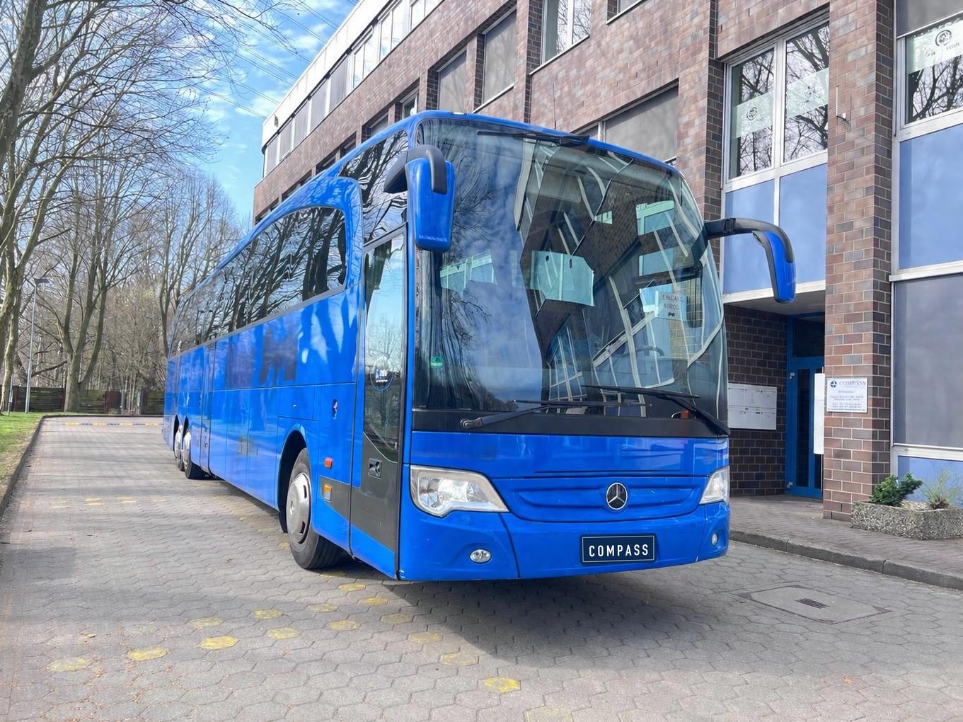 Blauer Mercedes-Benz Travego vor dem Compass-Büro