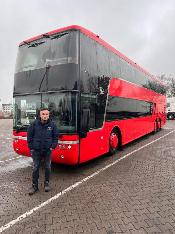 Obaidullah Karimi vor einem roten Van-Hool-Doppeldecker